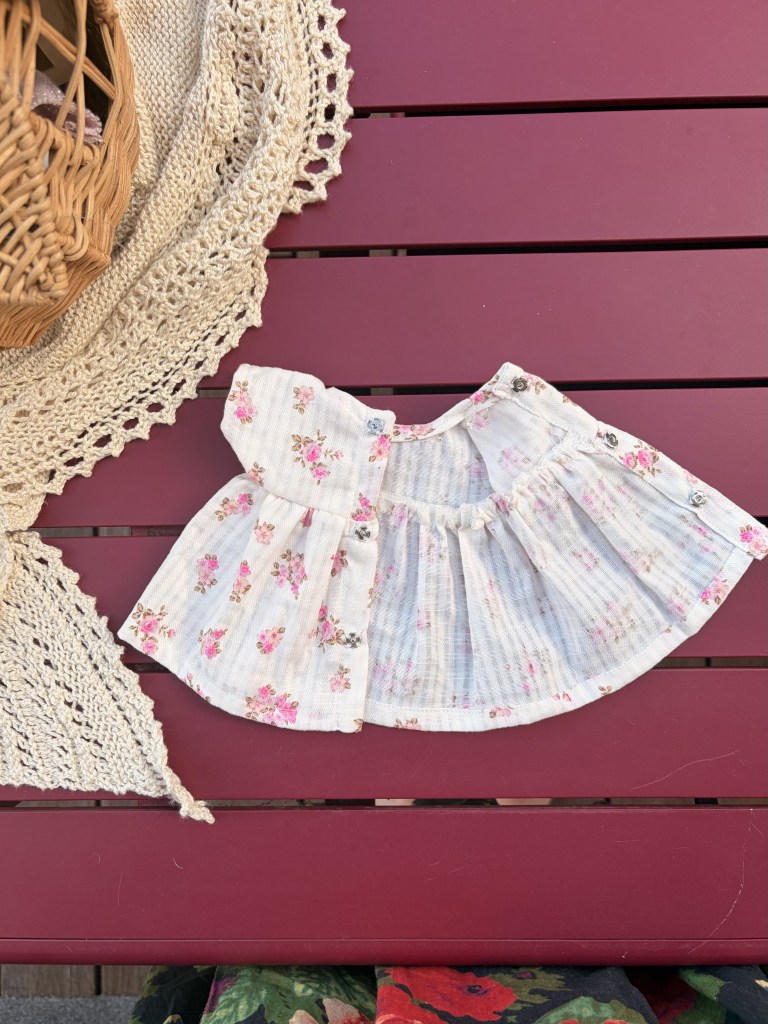 Une petite robe à fleurs roses sur une table rouge.